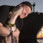 Photo of professional pet photographer, J.B. Shepard, in front of the Baltimore Inner Harbor, seen posing with a pit bull rescue dog from a local foster group.